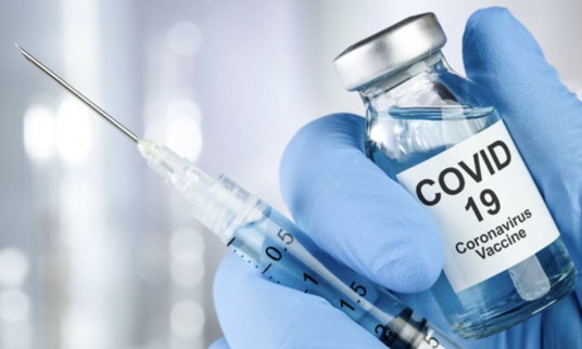 Healthcare cure concept with a hand in blue medical gloves holding Coronavirus, Covid 19 virus, vaccine vial