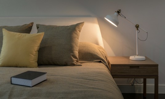 Cozy bedroom interior with book and reading lamp on bedside table